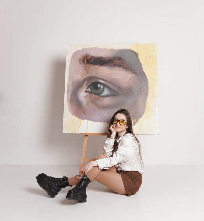 Michaela Vreja seated beside one of her paintings